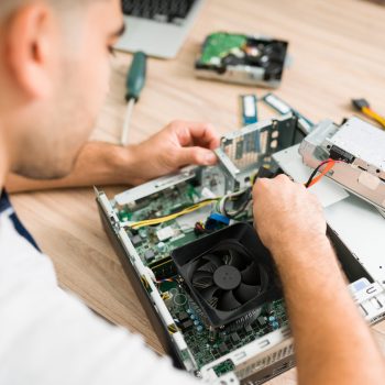Top view of a hispanic technician fixing the computer fan. Young man connecting a new component part in a CPU